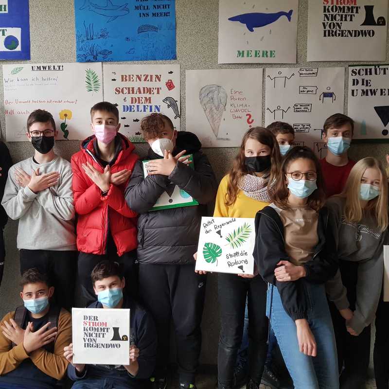 Schulklasse vor Wand mit Klimaplakaten